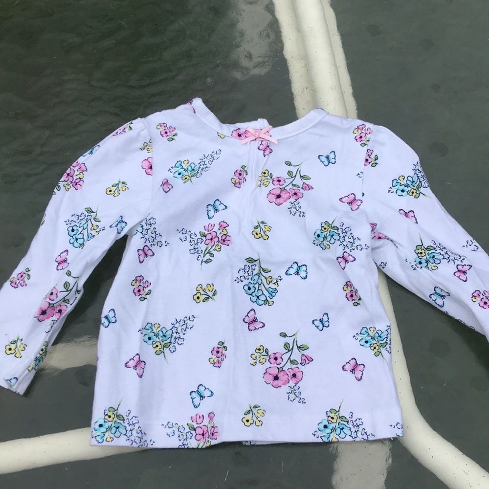 White flowered shirt with ruffles coming from bow.